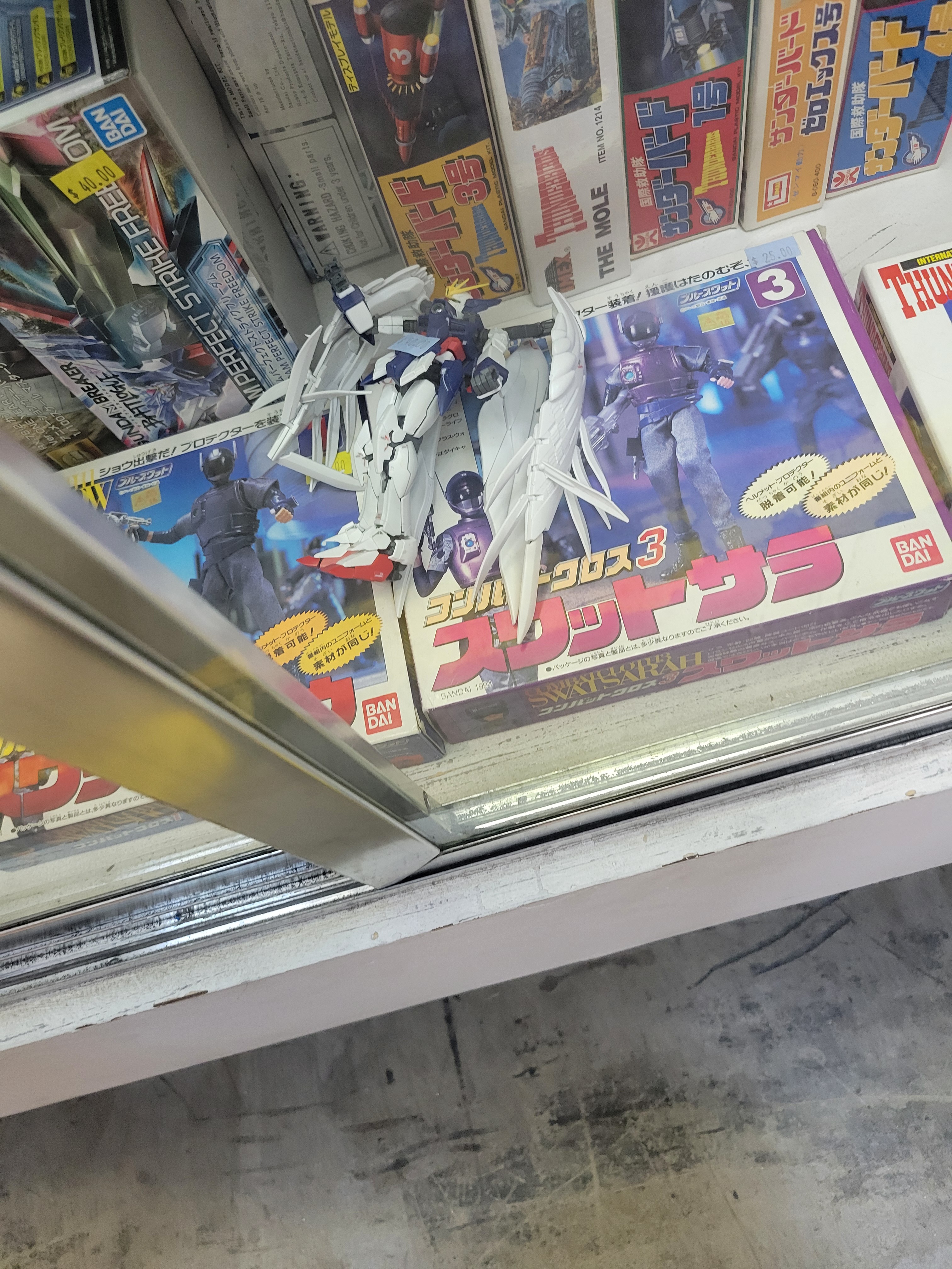 Gundam wing zero on top of and next to model kits.